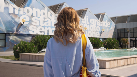 Young woman standing in front of a fountain and Humanities field building of Roma Tre University with a mural