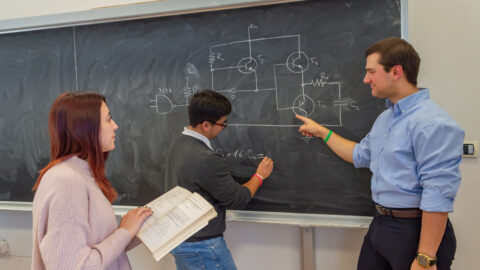 students in the classroom at the blackboard with the professor