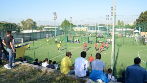 people in the stands watch a match on the football field